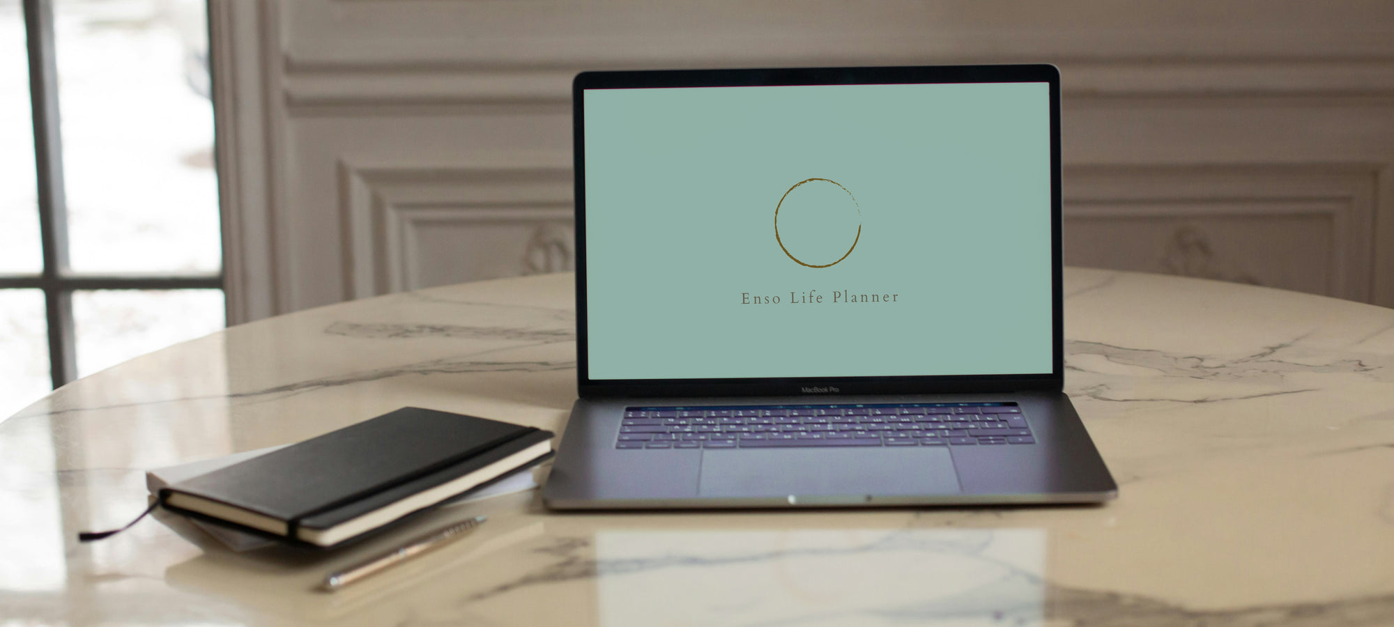 Enso Lifestyle Planner on pc screen with notebooks on the desk